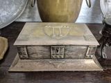 a silver box sitting on top of a table next to a vase