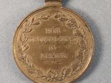 an old medal with a ribbon around it on a gray surface