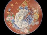 une assiette ornée de fleurs et d'oiseaux sur fond noir