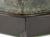 bronze statue of a dog on a pedestal on a white surface
