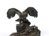 bronze statue of a bird on a rock on a white background