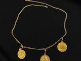un collier en or orné de trois pièces d'or sur fond noir