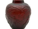 un vase rouge orné d'un motif sur un fond blanc