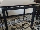 une table et des chaises dans une pièce, avec un tableau accroché au mur derrière elles