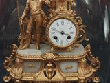 a gold clock under a glass dome on a table