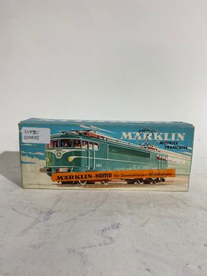 un vieux petit train en jouet est posé sur une surface blanche