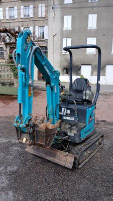 a small blue excavator that is parked on the street