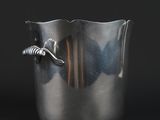 a silver vase with a fish in it on a black background