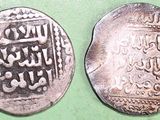 two silver coins with arabic writing on them on a green surface