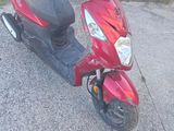 a red scooter parked on the side of the road