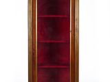 an antique wooden display cabinet with glass doors and a red velvet cover