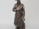 une vieille statue en bronze représentant un homme portant un chapeau et un manteau