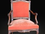 une vieille chaise dont l'assise est recouverte d'un tissu rouge sur fond noir