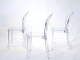 three clear plastic chairs sitting next to each other on a white surface