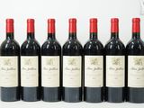 six bouteilles de vin rouge alignées sur une surface blanche