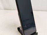 a black cell phone on a stand on a white surface