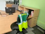 a desk with a computer and a yellow vest on it