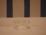 a small glass bowl sitting on a table with a striped wall in the background