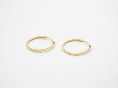 une paire de boucles d'oreilles en or sur fond blanc