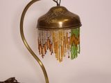 une photo d'une lampe de table surmontée d'un abat-jour orné de perles