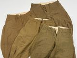 Trois paires de pantalons pour homme sont alignées sur une surface blanche
