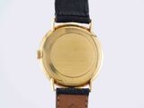a close up of a gold watch with a black leather strap