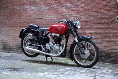a red motorcycle parked in front of a brick wall