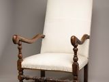 an old wooden chair with a white upholstered cushion on it