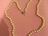 collier de perles orné d'un pendentif en forme de papillon sur fond rose