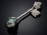 a close up of a black pearl and diamond broochle on a black surface
