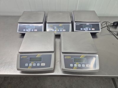 quatre balances électroniques posées sur une table dans une pièce