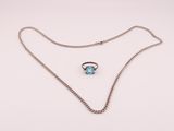 un collier en argent orné d'une pierre bleue et d'une chaîne, sur fond blanc