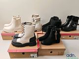 Plusieurs paires de bottes noires et blanches sont exposées dans une boîte