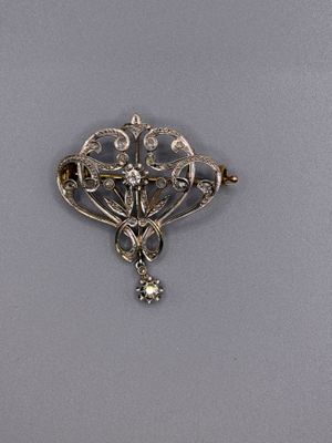 an antique silver broochle with flowers and leaves on it