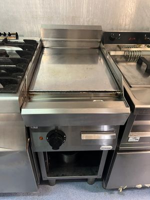 Plusieurs cuisinières en acier inoxydable sont alignées dans une cuisine