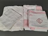 quatre serviettes blanches à bordures roses et ornées d'un monogramme