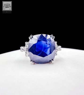 a close up of a blue sapphire and diamond ring on a white surface