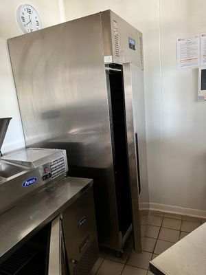 un grand réfrigérateur en acier inoxydable dans une cuisine où est accrochée une horloge au mur