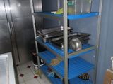 une étagère bleue sur laquelle sont posés des casseroles et des poêles, dans une cuisine