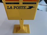 une boîte aux lettres jaune posée sur une table blanche