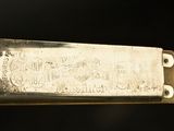 a silver plate with a stamp on it on a black background