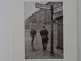 black and white photograph of two men walking down a cobblestone street