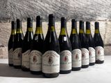 several bottles of wine are lined up in a row in front of a stone wall