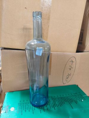 une bouteille en verre bleue posée sur une boîte verte