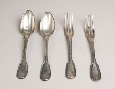 quatre cuillères en argent et une fourchette sont alignées sur une surface blanche