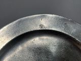 someone is holding a silver plate with a small black object in it