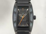 une montre noire avec un cadran noir et des aiguilles orange