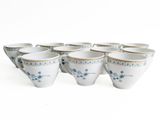 six blue and white coffee cups are lined up on a white surface