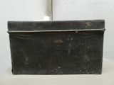 une vieille valise noire posée sur une chaise blanche