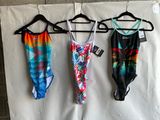 three swimsuits hanging on a clothes hanger on a wall